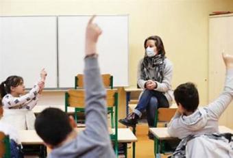Female teacher wearing a mask in front of class
